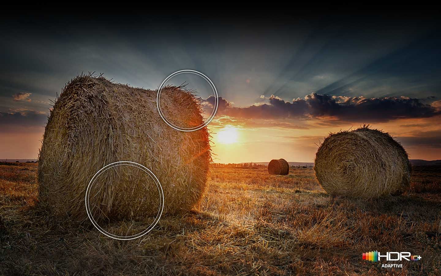 The sun is setting over a wide field with emphasis on a large hay stack. The scene after applying HDR 10 ADAPTIVE/GAMING technology is much brighter and crisper than the SDR version.